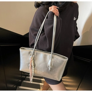 Détail du sac cabas argenté avec logo embossé et ornements suspendus très élégants