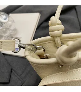 Detail of light beige bucket bag with litchi grain leather and silver hardware