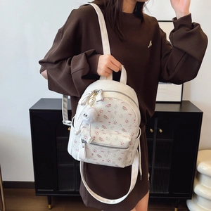 Sac à dos blanc à fleurs avec nœuds et pendentif en peluche porté par un mannequin