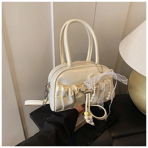 Detail of cream pleated bowling bag featuring lace bow, pearls and silver zipper