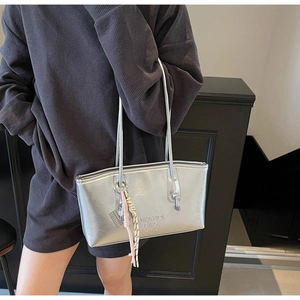 Close-up of a silver metallic tote bag with embossed letters and braided charm detail