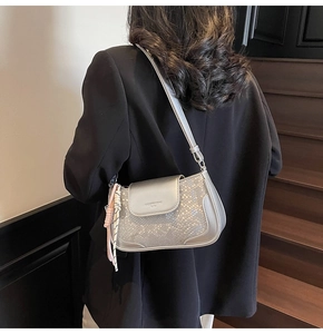 Silver-grey faux snake leather underarm bag worn by a model in a black suit