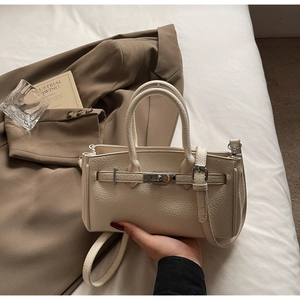 Detailed view of cream lychee leather handbag featuring silver twist lock and strap