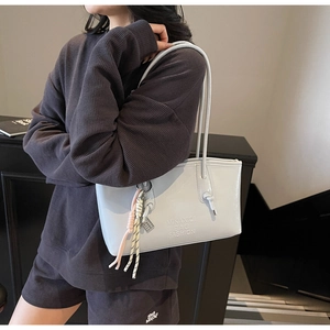 Détail du sac cabas gris clair avec texte en relief et pendentif en corde tressée