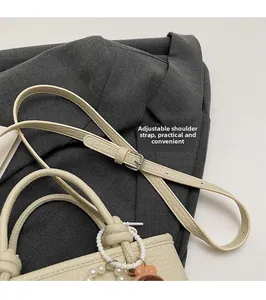 Detail of adjustable leather strap and cream bucket bag with pearl pendant decor