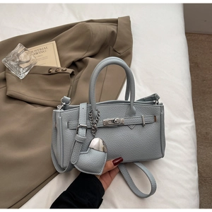 Close-up of litchi pattern leather handbag with silver lock and heart charm