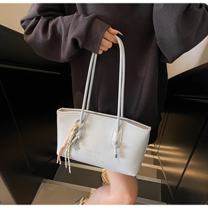 Détail du sac à épaule en cuir brillant bleu clair avec texte embossé et breloque