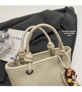 Close-up of pebble leather bucket bag featuring round padded handle and cute doll charm