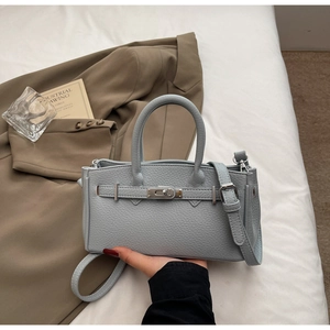 Detail shot of light blue lychee pattern leather bag with silver metal turn-lock and strap