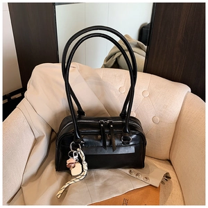Detail einer schwarzen Boston Bag aus Leder mit Doppelreißverschluss und dekorativem Anhänger