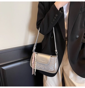 Detail of silver metallic crossbody bag with snakeskin texture and tassel charm