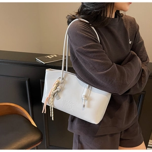 Détail du sac cabas blanc brillant avec logo embossé et pendentif en corde tressée