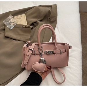 Detailed macro of pink lychee textured leather handbag with a matching heart charm accessory
