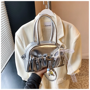 Close-up of metallic silver pleated bag with pearl charms and lace bow detailing