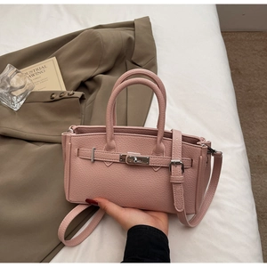 Close-up of pink lychee leather handbag featuring classic silver rotating metal buckle