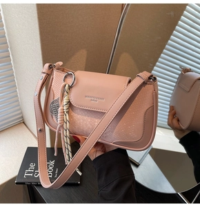 Detail of pink snake-embossed leather handbag with woven rope charm and brand logo