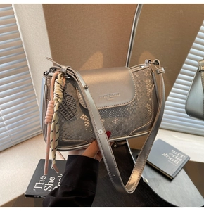 Detail of silver crossbody bag with snake-skin texture and colorful woven pendant