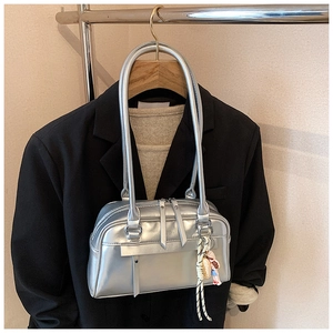 Detail der silbernen Spiegel-Schultertasche mit Doppelriemen und stylischem Anhänger
