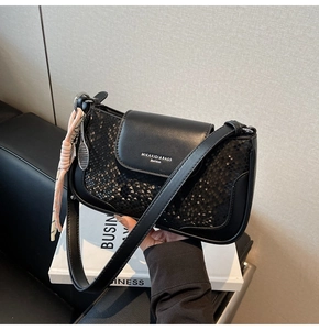 Detail of black snake-embossed square shoulder bag with a pink woven tassel pendant