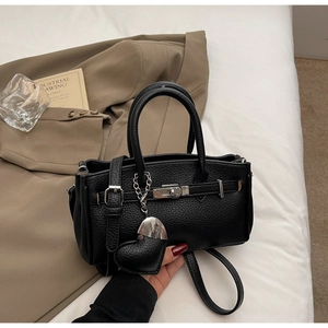 Detail of black lychee grain leather mini handbag with silver twist lock and heart charm