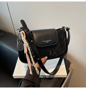Detail of black snake-textured shoulder bag with creative tennis racket charms