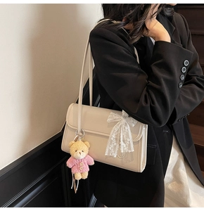 Close-up of cream shoulder bag with lace bow and cute plush bear charm detail