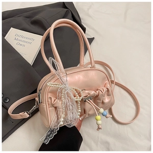 Detail of light pink ruched handbag with lace bow, pearls, and glossy leather texture