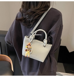 Close-up of textured light blue bucket bag featuring a cute mascot and pearl charm