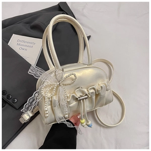 Detail of pleated beige Boston bag with lace bow, pearls, and colorful bead tassels