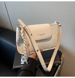 Close-up of minimalist cream white square bag with faux snakeskin texture and brand logo
