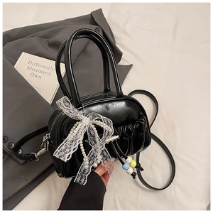 Detail of black patent leather Boston bag with pearl lace bow and beaded pendant