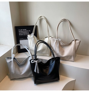 Detailed view of four tote bags in black, white, grey and beige with lace bow handles