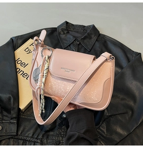 Close-up of pink snake pattern crossbody bag with tennis racket charm and leather strap