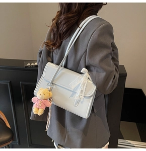 Detail of light blue glossy faux leather shoulder bag with cute teddy bear charm