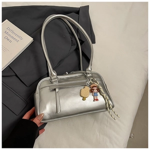 Detail der silbernen Metallic-Tasche mit süßen Anhängern und gewebtem Knoten-Dekor