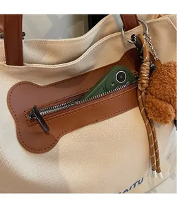 Detalle del bolso de lona con bolsillo de cuero marrón y colgante de oso de peluche decorativo
