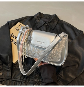 Macro detail of silver snake-patterned leather bag with textured finish and metal strap