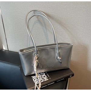 Detail of silver metallic tote bag with embossed letters and woven rope charm