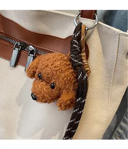 Primer plano de un colgante de peluche de perro marrón en un bolso de lona beige