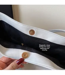 Detail view of the magnetic gold snap closure on a white faux leather tote bag