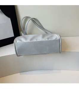 Detail view of reinforced bottom seams and dual handles on a grey soft leather tote bag