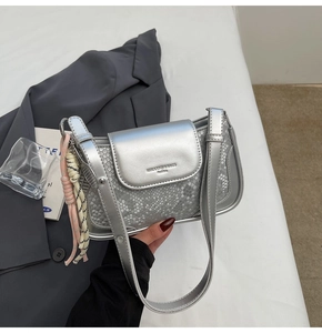 Detail of silver crossbody bag featuring snakeskin texture and braided rope ornament