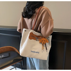 Close-up of beige canvas tote bag with brown leather accents and cute puppy charm