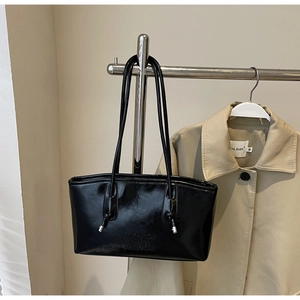 Détail d'un sac à bandoulière noir brillant avec des finitions en métal argenté