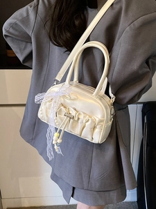 Chic ruched bowling bag in cream with lace bow and pearl charm worn by a model