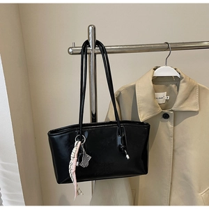 Détail d'un grand sac cabas noir en similicuir avec pompons et bandoulière fine