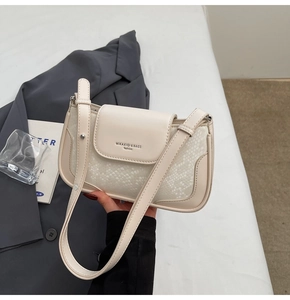 Detail of cream faux snake leather crossbody bag shown in a minimalist lifestyle setting