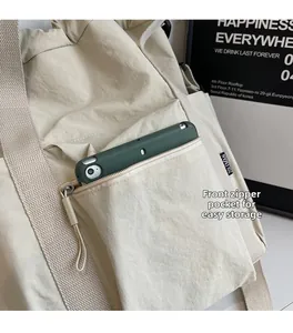 Detail of water-resistant off-white nylon tote bag with functional front zipper pocket
