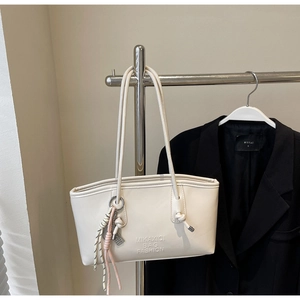 Détail du cabas blanc crème avec logo gaufré et décoration en anneau métallique