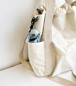 Close-up of the beige nylon tote bag side pocket holding a folded umbrella for utility